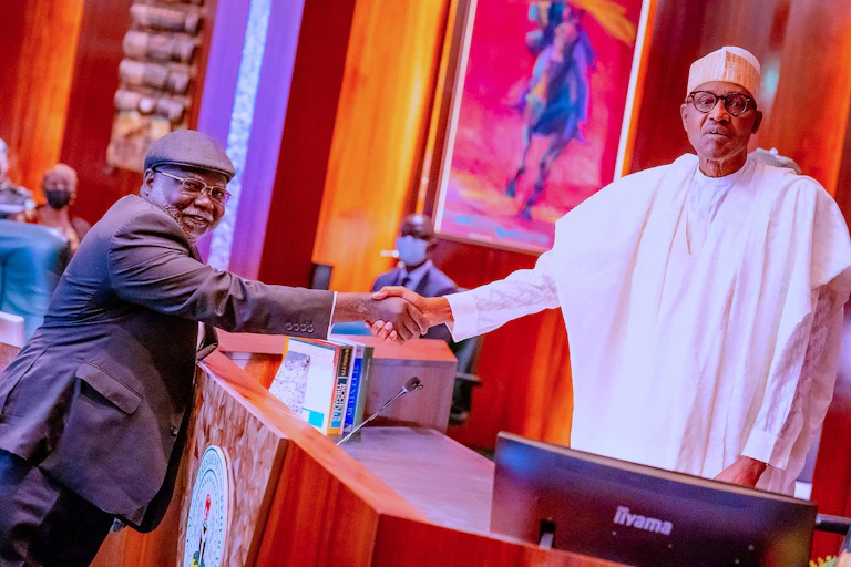 A man on grey suit in a handshake with another man on African traditional attire