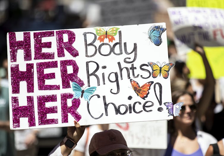 A protestor holding up a sign reading 'her body, her rights, her choice'