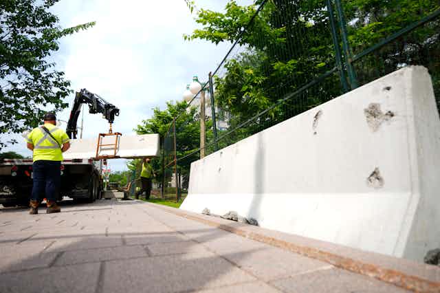 a worker watches as a concrete barricade is put into place