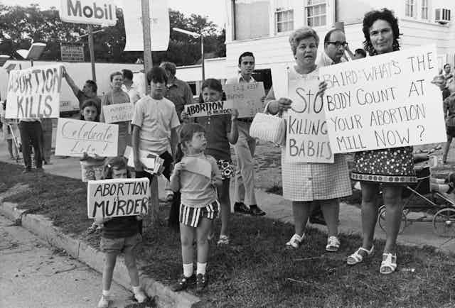 Black and white photograph of kids and adults holding anti-abortion signs.