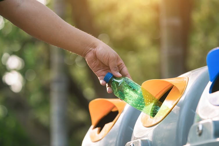 Person putting bottle in recycling bin