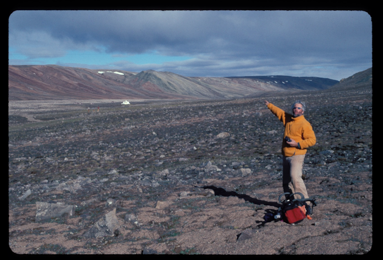 Man standing on rocky flat ground with mountains in the distance