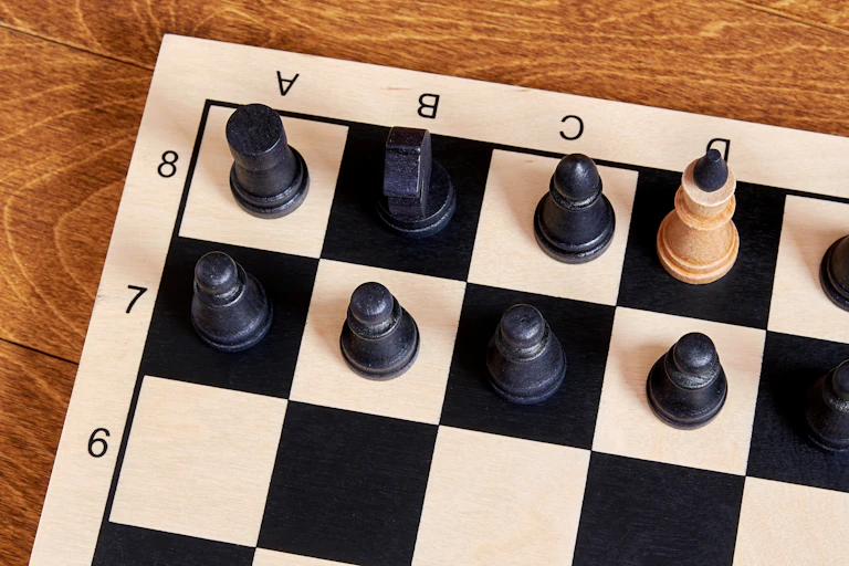 Chessboard with one white piece among black pieces.