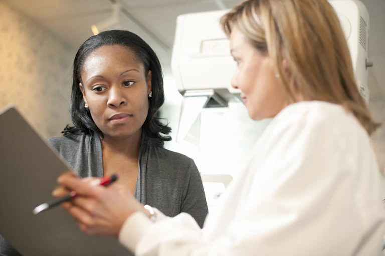 Technician showing patient clipboard next to mammogram machine
