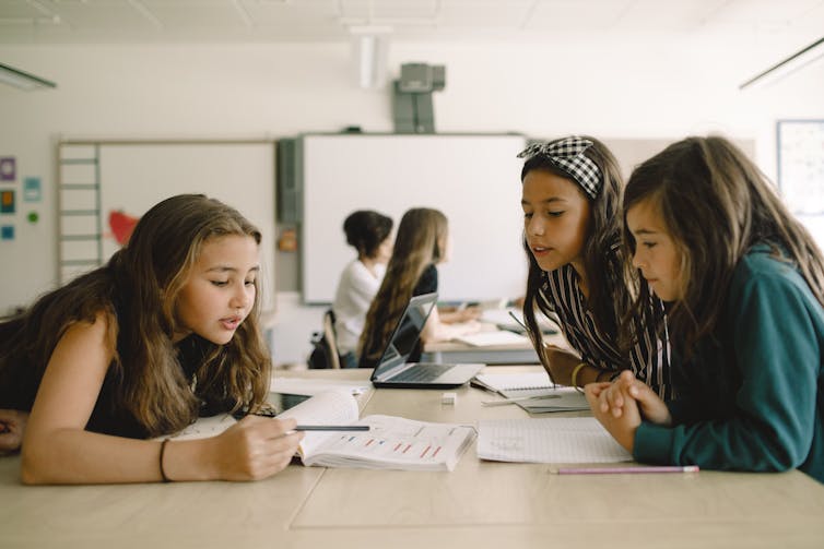 Three middle school students work on an assignment