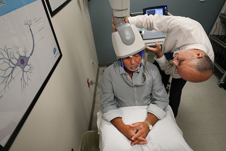 Doctor placing transcranial magnetic stimulation device on patient's head.