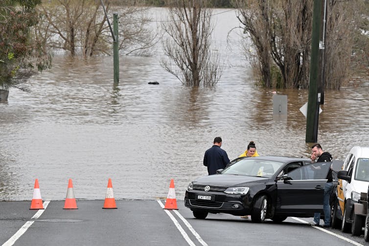 flooded road with cars parked and people standing