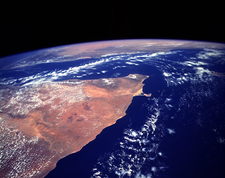 A view of the Horn of Africa from space, with brown land on the left and dark blue sea on the right of the image.