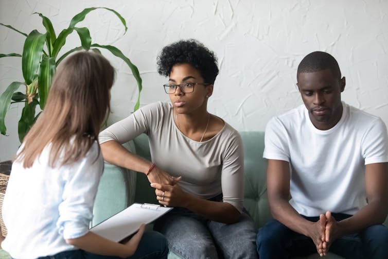 A young couple speaks with their female doctor in her office.