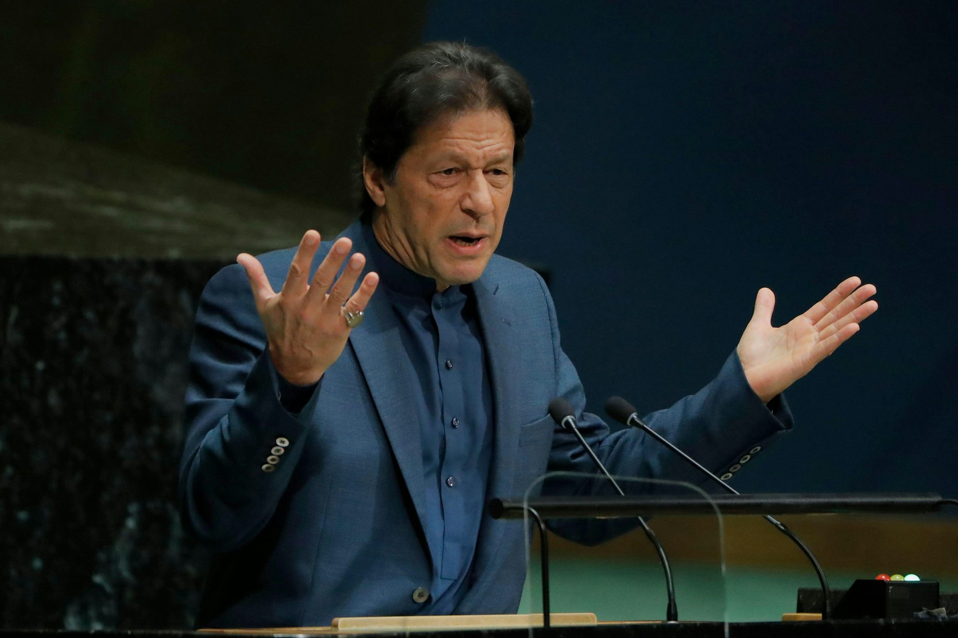 A man wearing a suit putting his hands in the air.