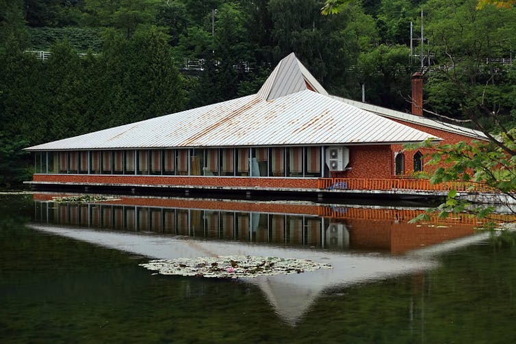 A shuttered restaurant by a lake in a park.