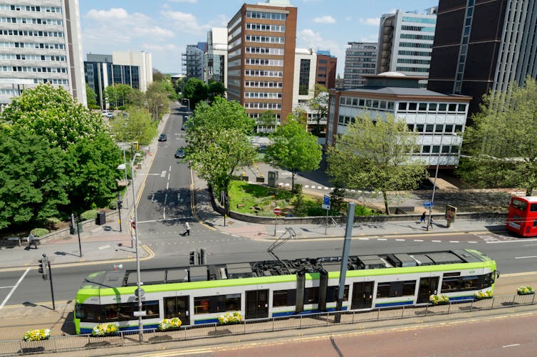 A green tram car in a residential area.