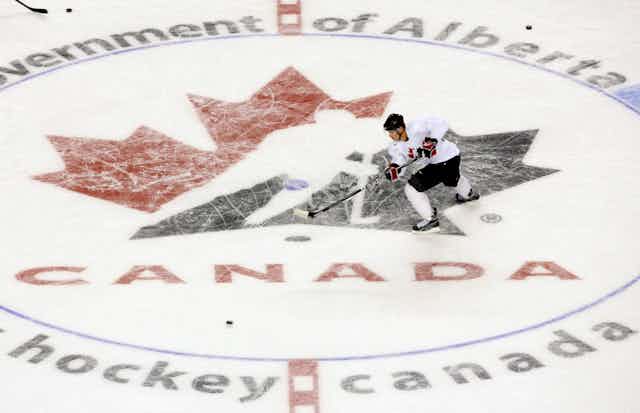 A man skates across the hockey canada logo on a rink