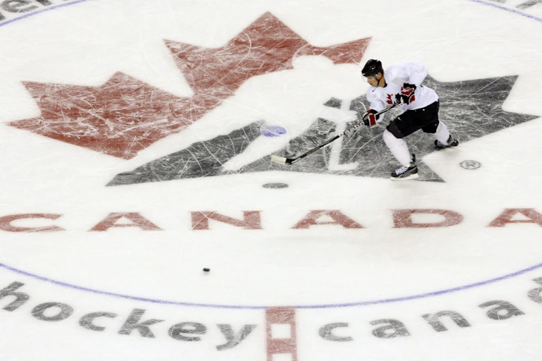 A man skates across the hockey canada logo on a rink