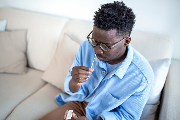 A man inserts a swab up his nose for a rapid test.