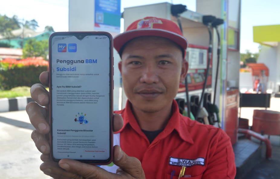 Petrol station officer showing how to register to MyPertamina app