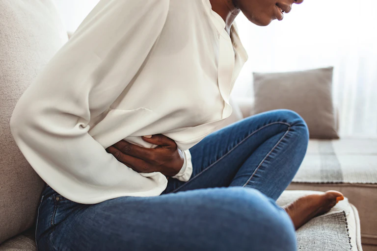 femme en douleur se tient le ventre