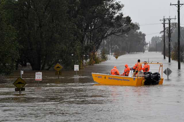 Rescuers in high-vis jackets on a boat in a flooded street  
