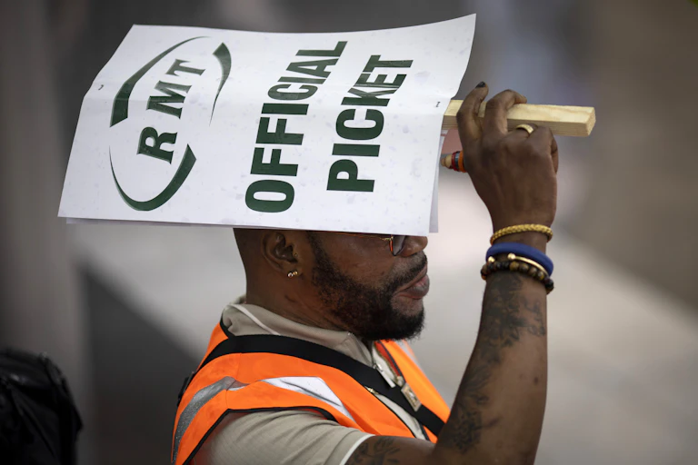 Man in high-vis jacket holding an RMT "official picket" placard