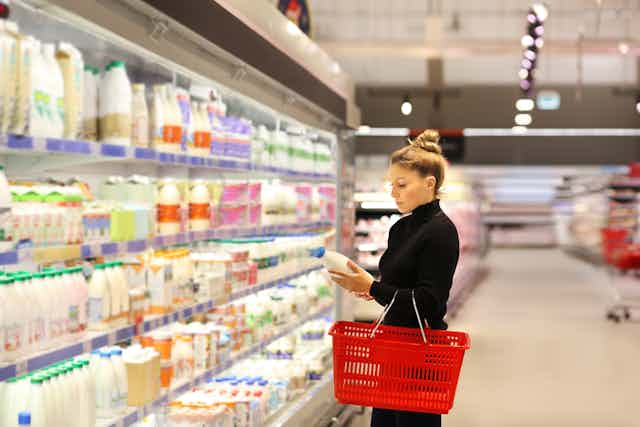 Una mujer ante el lineal de leches diversas de un supermercado.
