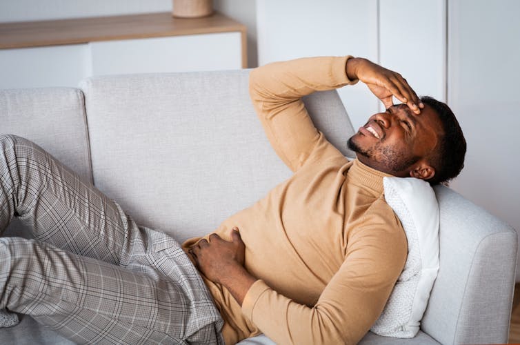 A man holds his stomach in pain.