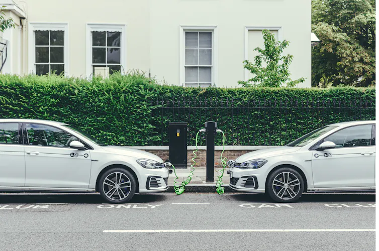 Two electric cars charging on street.