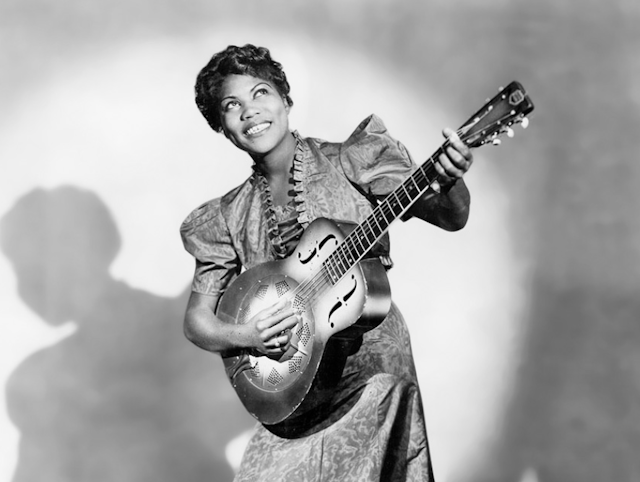 Black female singer with a guitar.