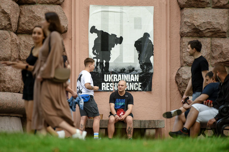 People going about their business in Kyiv, in the background a patriotic anti-war poster.