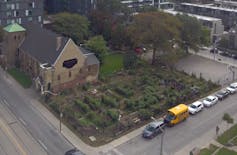 A church with city buildings behind it and a garden in the foreground