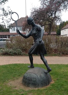 Bronze statue of tennis player Dorothy Round, in action with racquet in hand and wearing a skirt