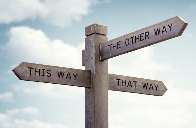 Signpost at crossroads saying 'this way', 'that way', 'the other way'