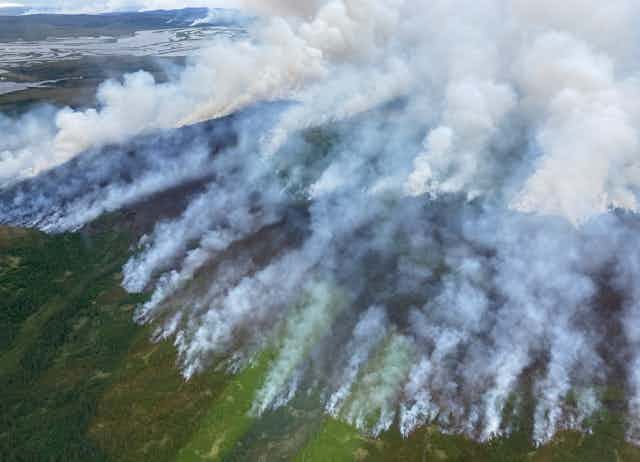 Smoke spills from fires along a line in tundra. 