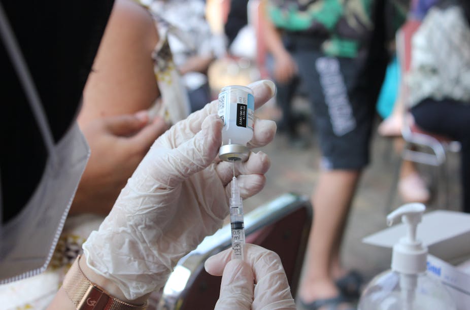 Gloved hands filling syringe with vaccine