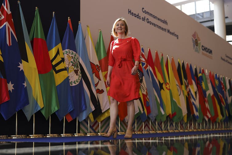 Liz Truss walking in front of a collection of national flags.