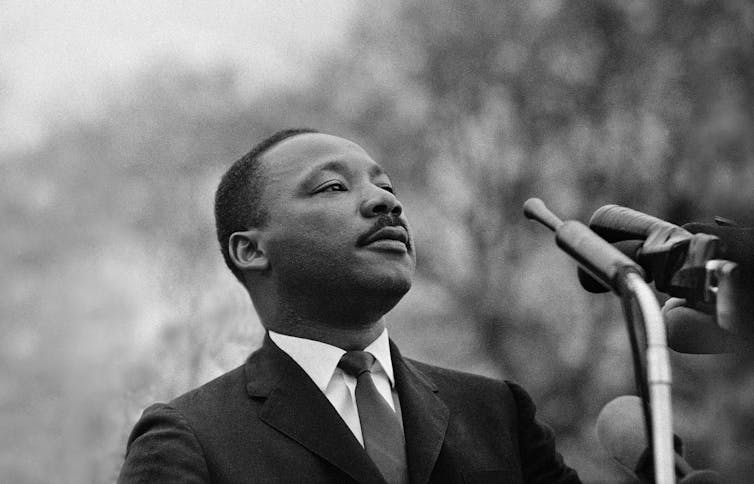 Martin Luther King is wearing a suit and looking to the right of the image