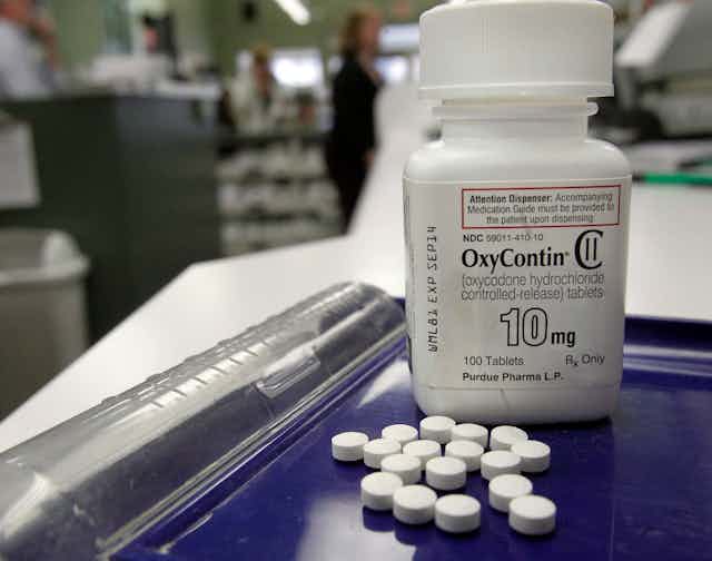 A pill bottle labelled OxyContin 10mg with loose pills in front of it