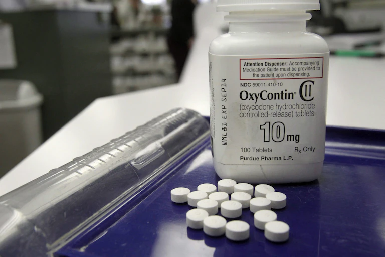 A pill bottle labelled OxyContin 10mg with loose pills in front of it