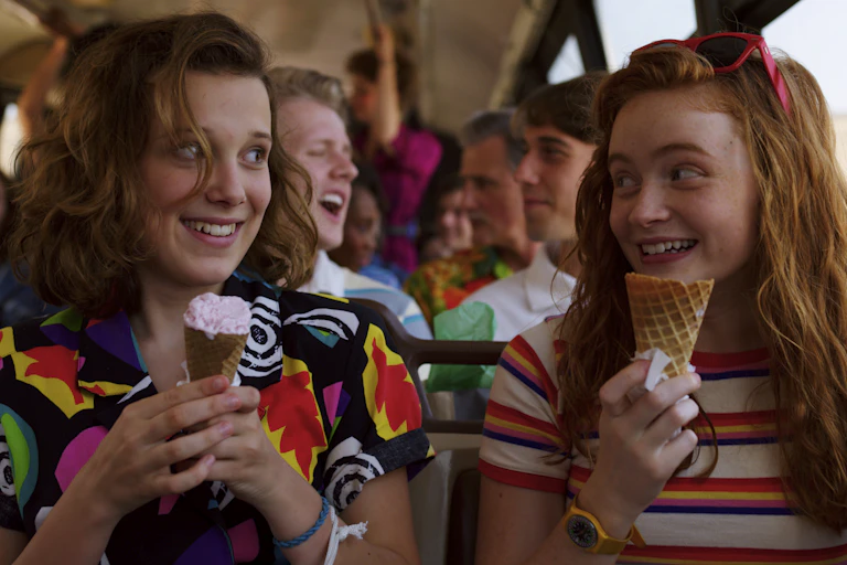 Two teenaged girls eating ice cream on a bus
