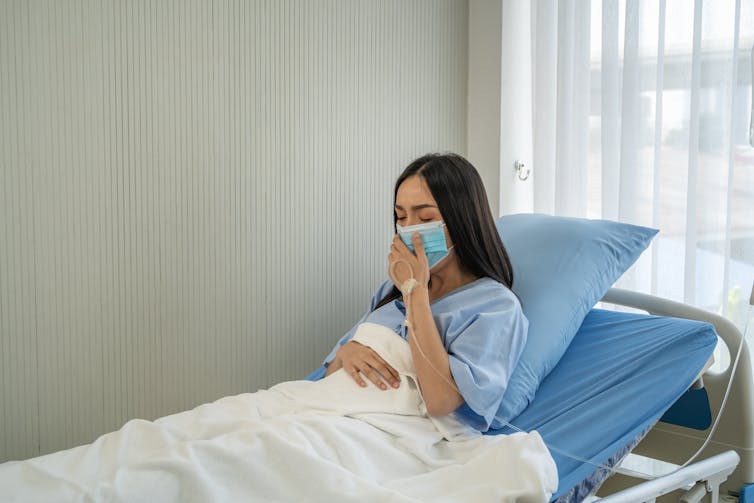 Woman in hospital bed with mask on