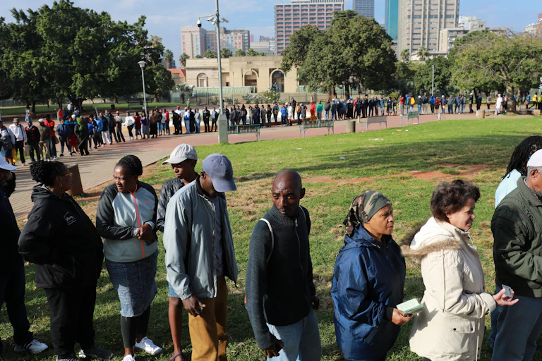 Man and women stand in a long queue.