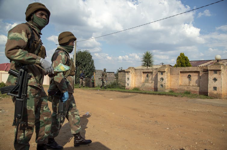 two armed soldiers patrolling a dusty street