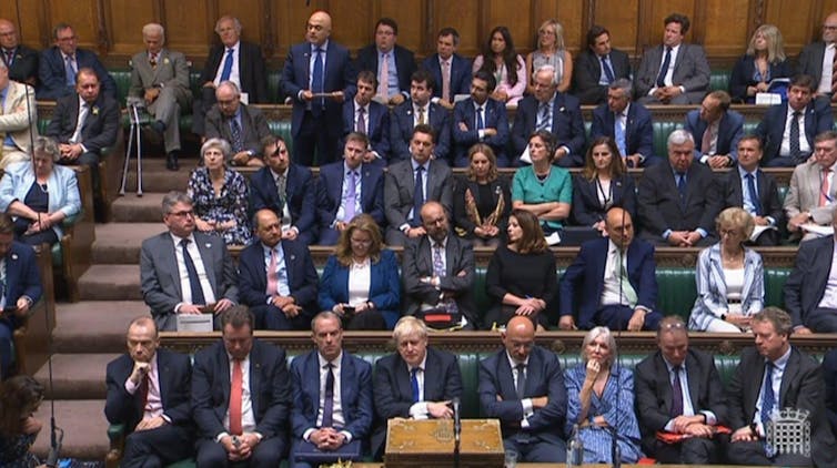 Conservative MPs looking tense on the benches of the House of Commons.