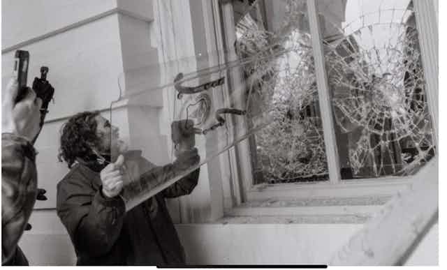 a man smashes a window using a shield.