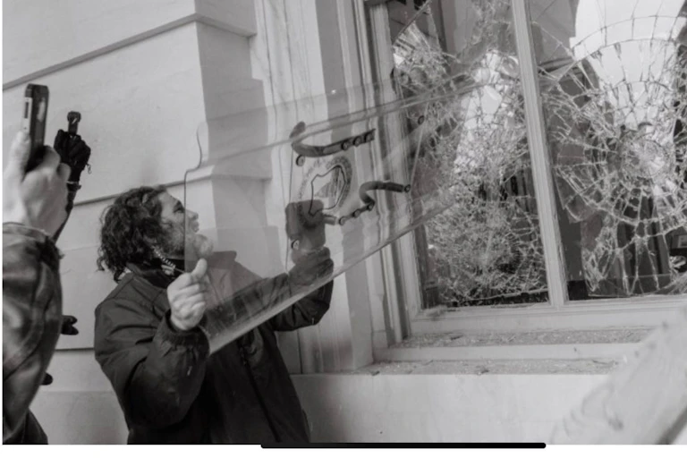 a man smashes a window using a shield.