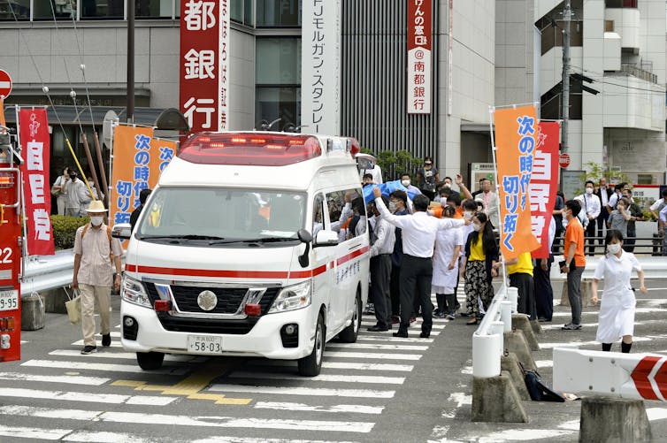 An ambulance on the street surrounded by people