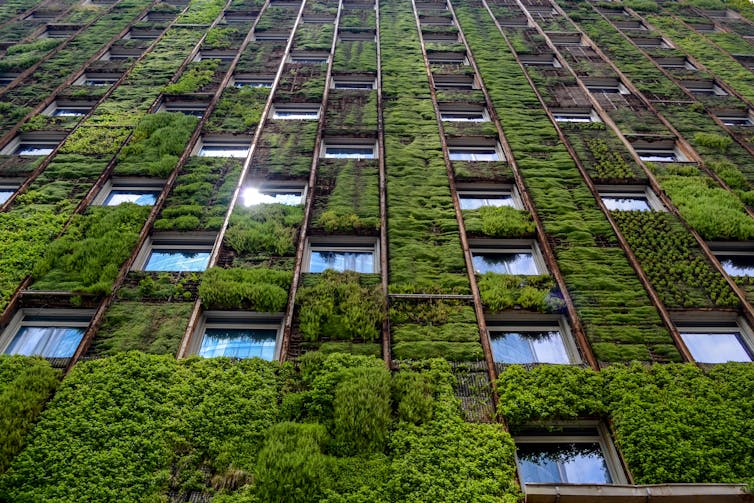 a tall building covered in plants on the outside walls