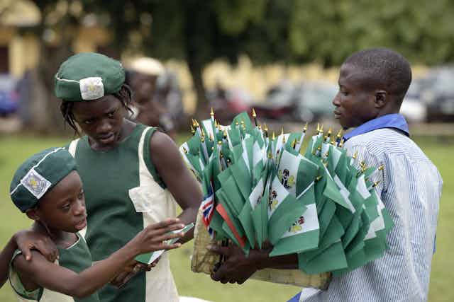 A vendor carries Nigerian national flags on October 1, 2015 as part of Nigeria's independence anniversary celebrations, in Lagos.