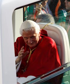 Pope Benedict XVI sitting in his popemobile, waving to crowds.