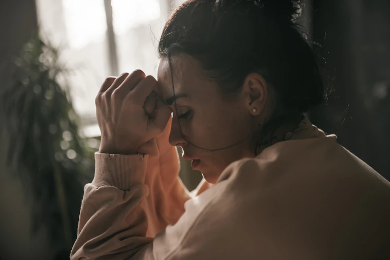 Midsection of a woman clasping her hands and looking down