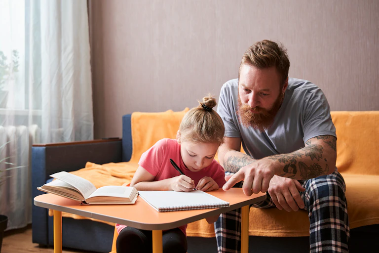A father works with his daughter on a writing task.
